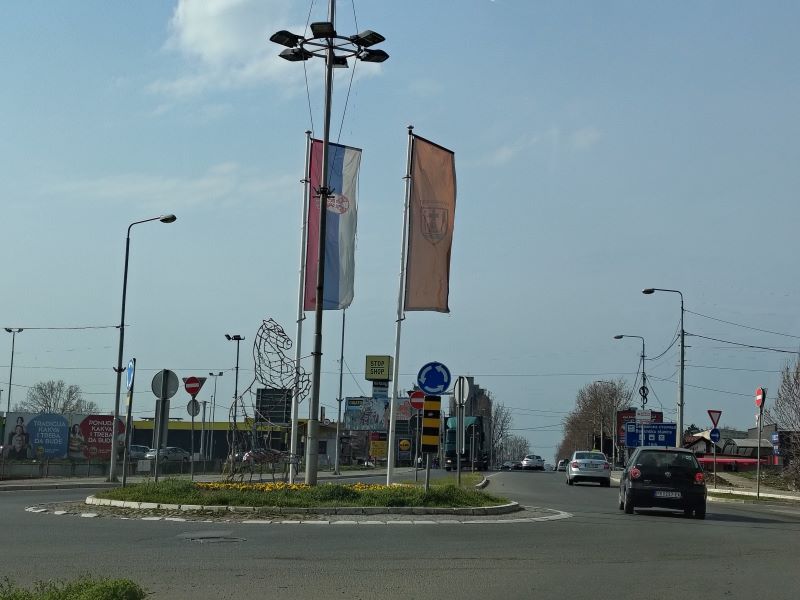 Oblačno vreme iznad kružnog toka dok automobili prolaze kolovozom kroz gradski saobraćaj.